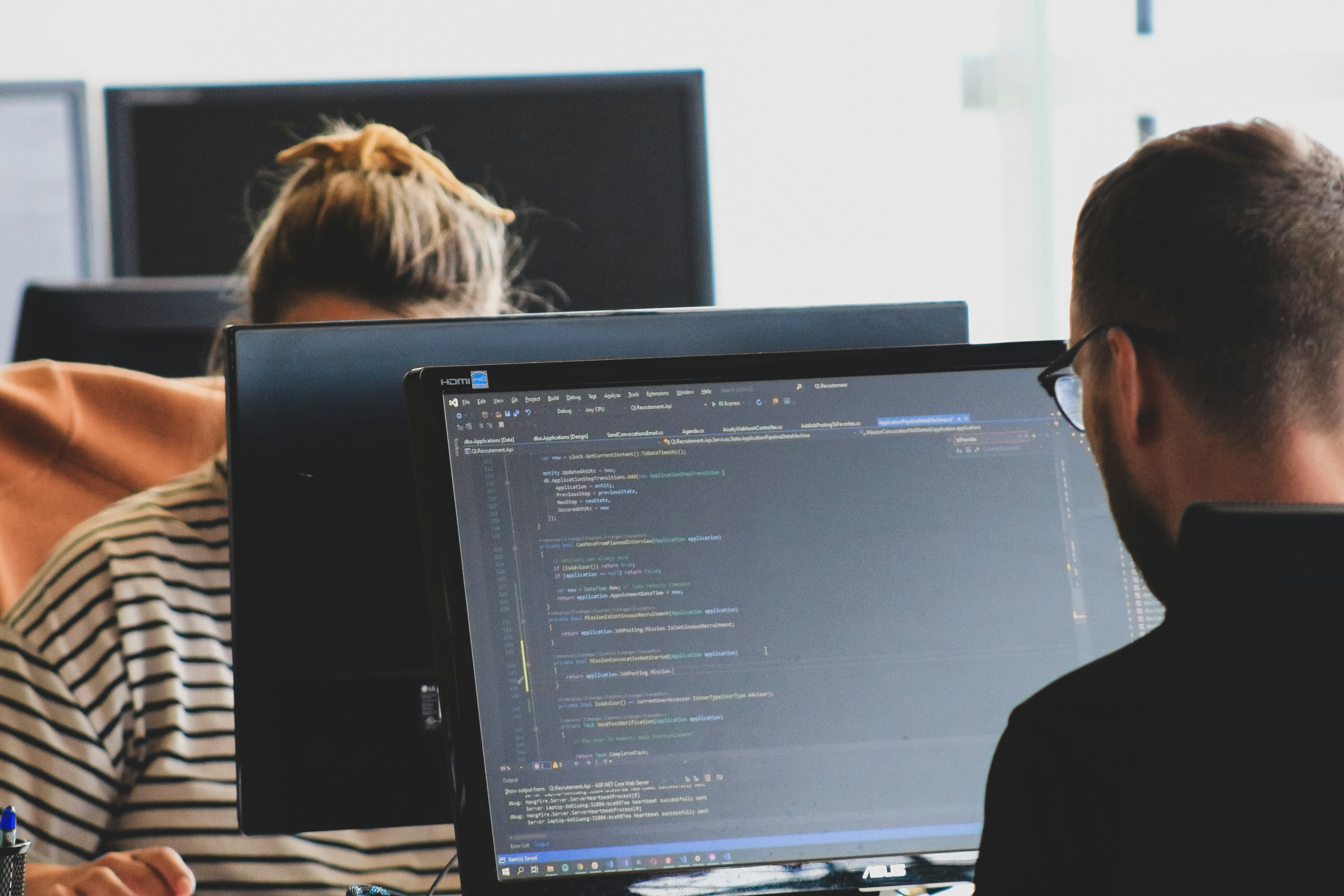 Two software developers working at computer monitors with code on screen